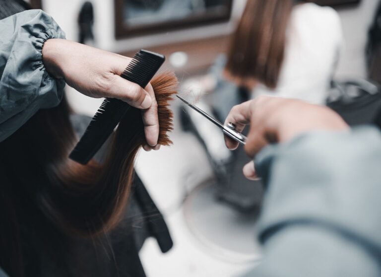 Stylist cutting a client's hair with scissors and comb in a salon