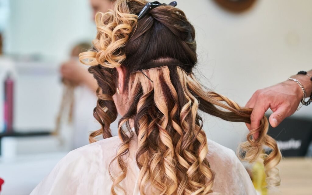 Hairstylist perfecting curls on a woman's hair in a salon